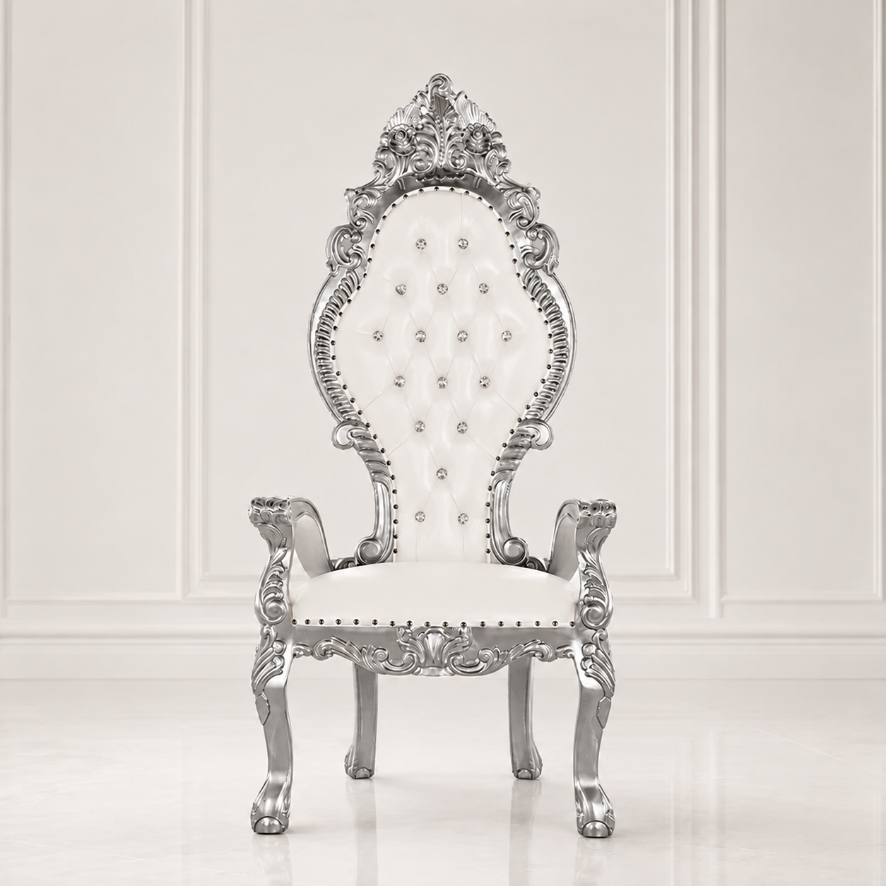 An ornate baroque-style throne chair with a carved silver metal frame and a white tufted upholstered seat and backrest, set against a white paneled wall.