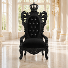 A black ornate baroque-style throne chair with a crown on the backrest, set in a grand, sunlit palace hall with marble floors and white columns.