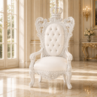 An ornate white throne-style armchair with a crown on the backrest, tufted button detailing, and carved decorative woodwork, placed in a bright classical interior with large windows and polished floors.